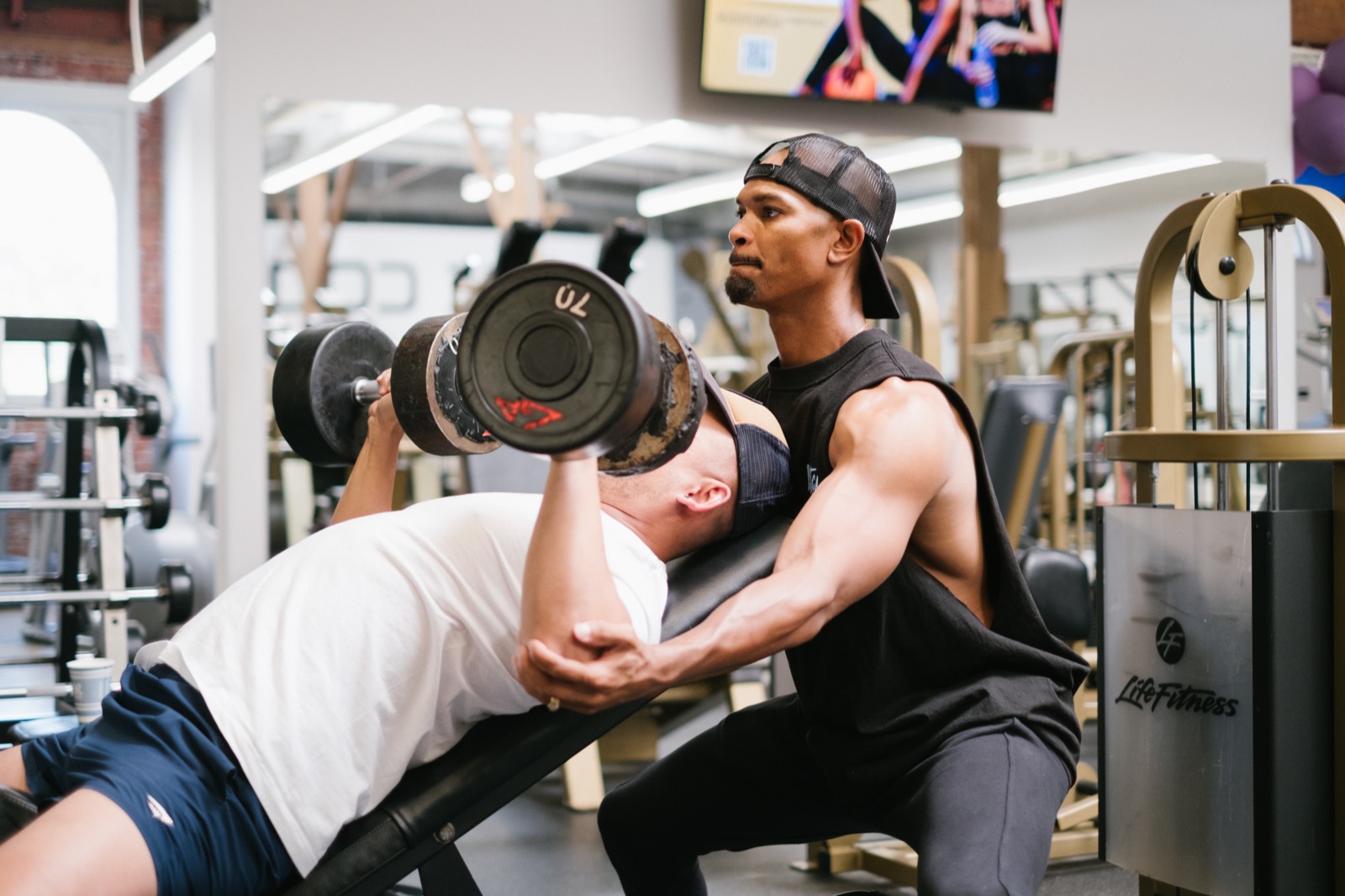 A WESTCA coach spotting a client on a dumbbell bench press